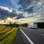 Bus,Traveling,On,The,Asphalt,Road,In,A,Rural,Landscape